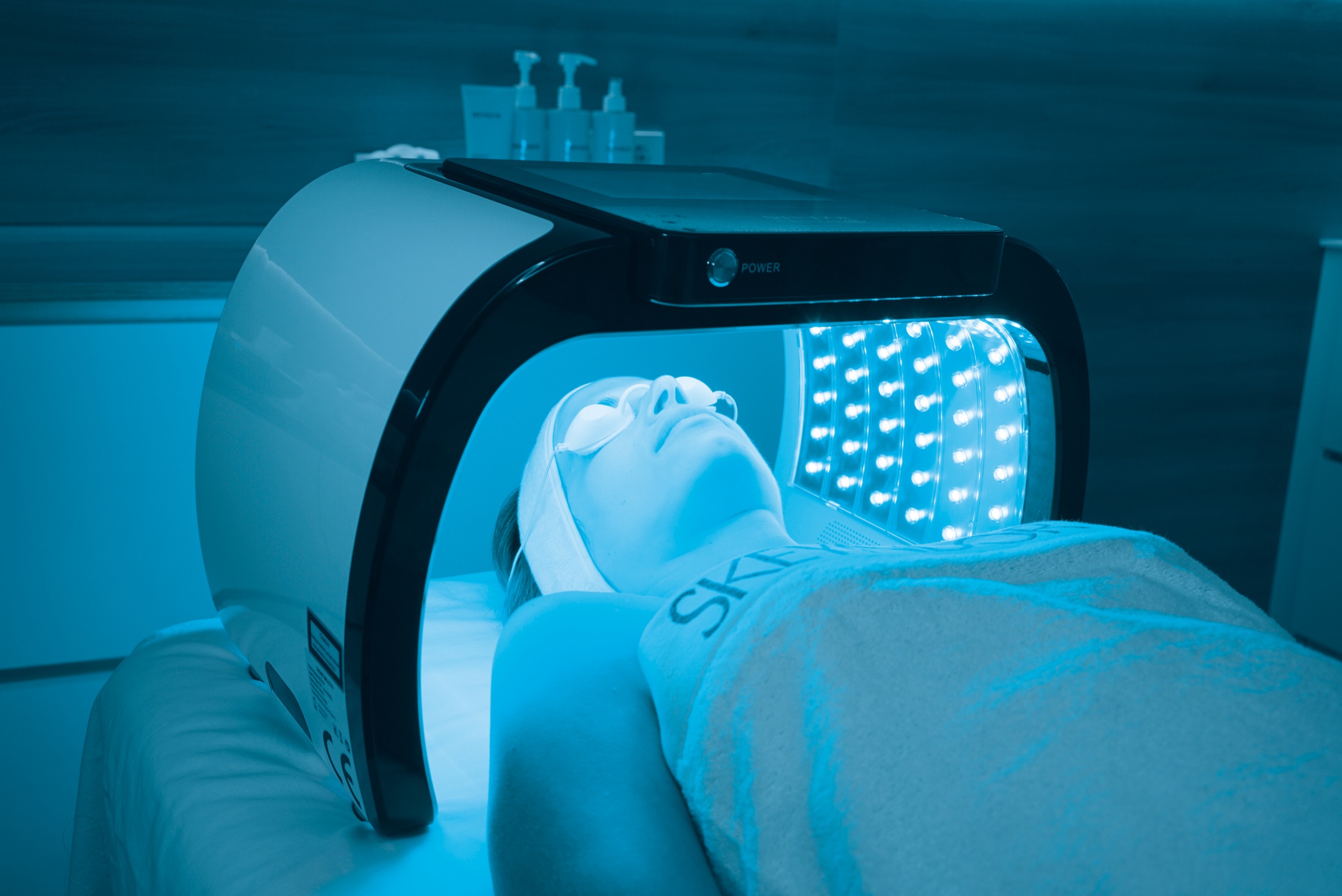 A client under the DermaLED canopy in blue light — the SKEYNDOR+ Protocol